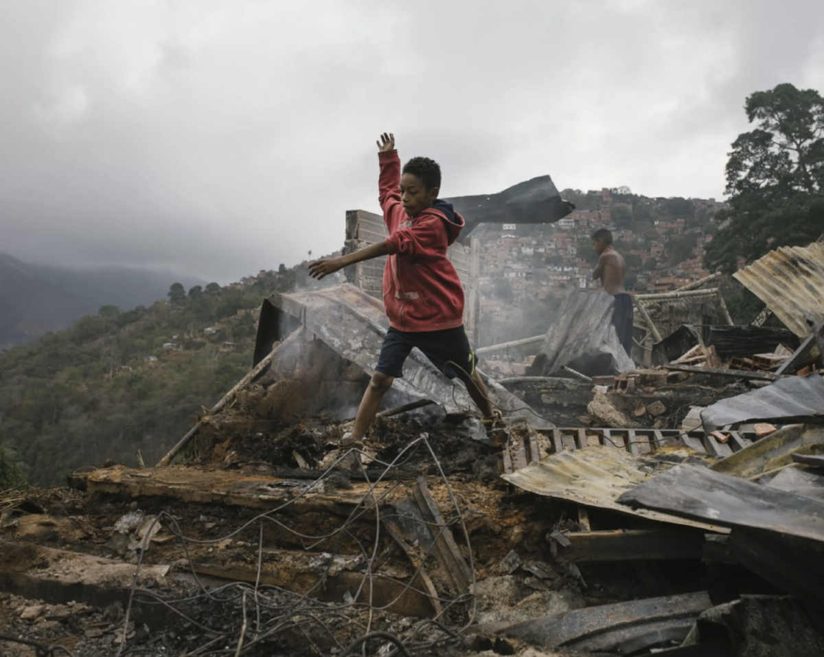 A boy moves on top of the debris from a fire in San Isidro, Caracas, Venezuela, on February 18, 2019.